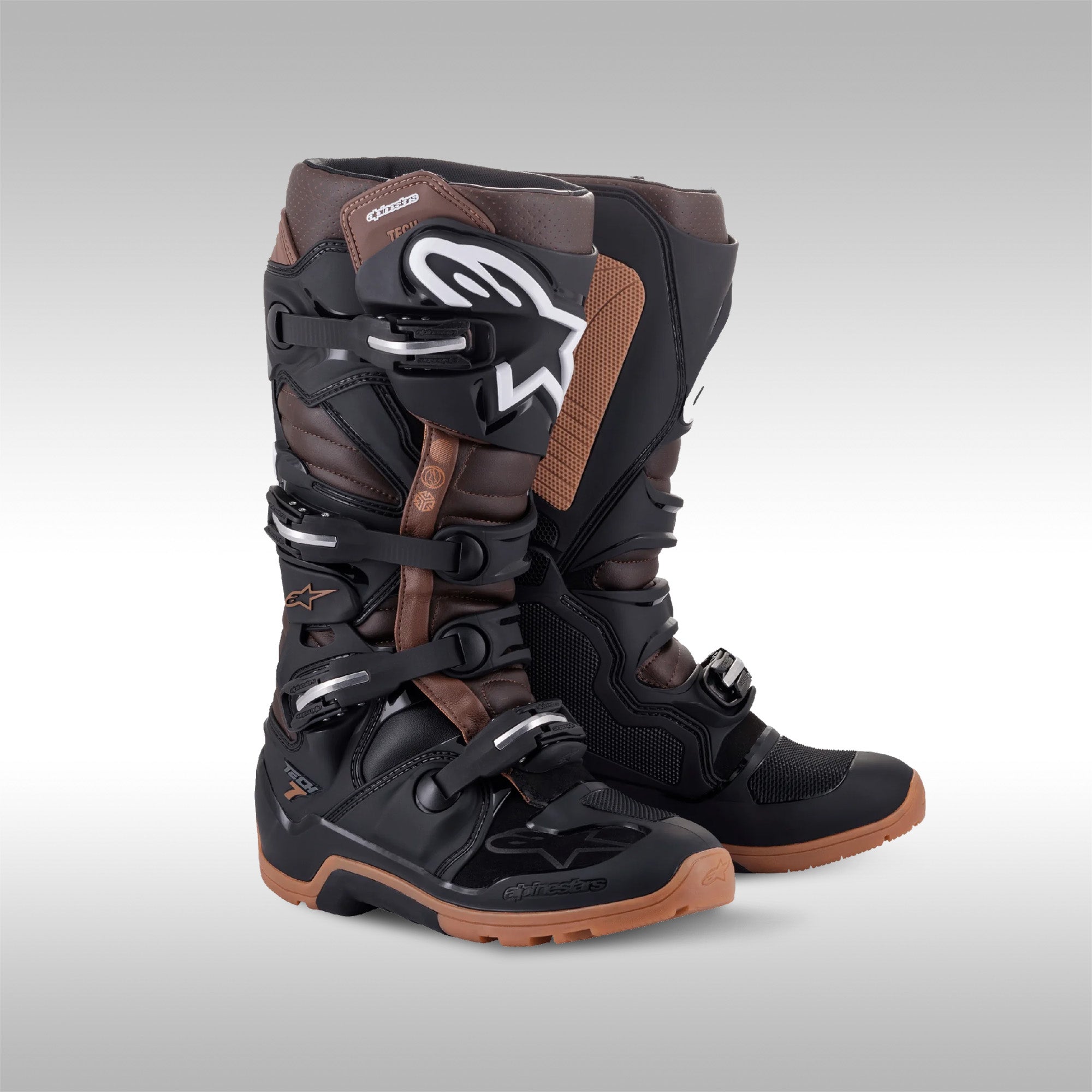 Alpinestars Tech 7 Enduro boots in the Black and Dark Brown option. The left and right boot next to each other. Enduro and dualsport motorcycle boots. Protective gear for dirtbike riding.