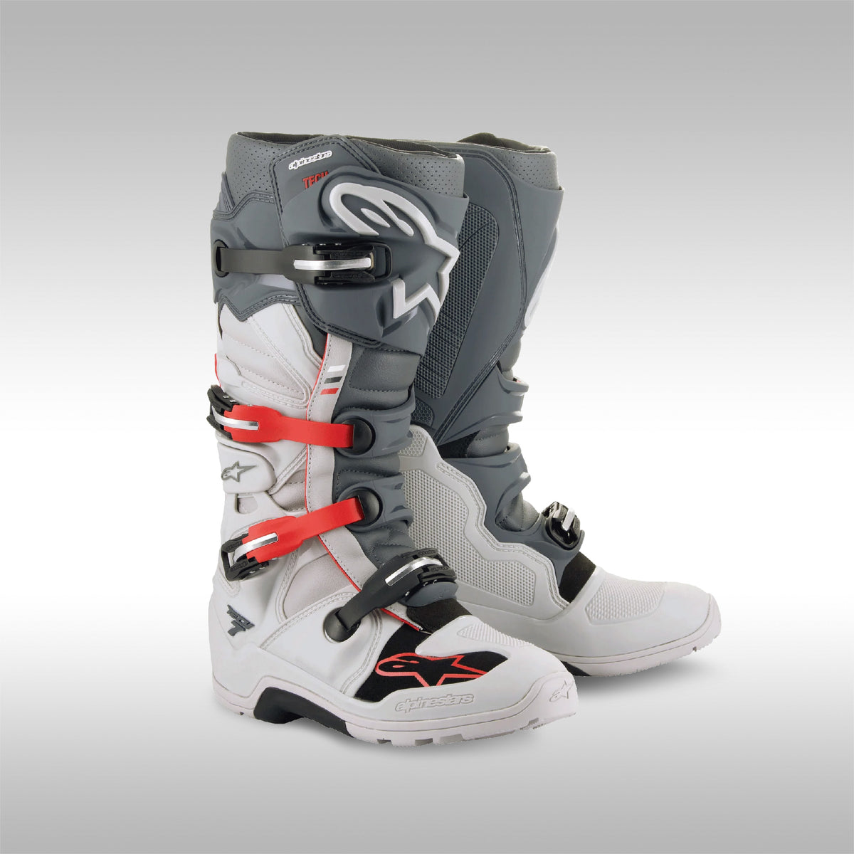 Alpinestars Tech 7 Enduro boots in the Light Gray, Dark Gray with Bright Red accent option. The left and right boot next to each other. Enduro and dualsport motorcycle boots. Protective gear for dirtbike riding.