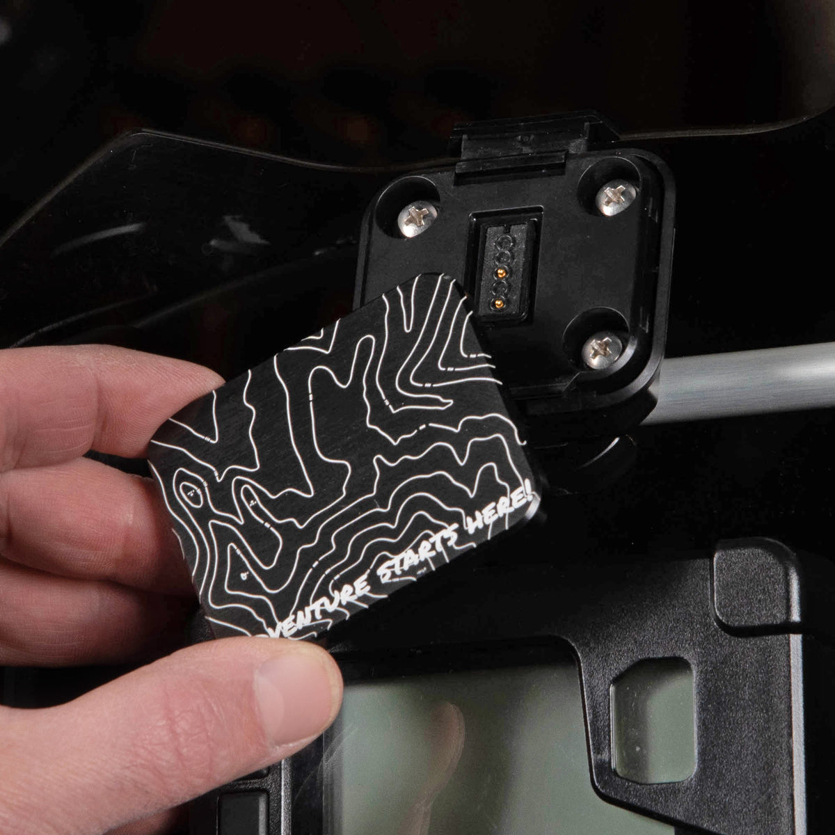 In hand shot of the MotoPumps aluminum gps mount cover with the TOPO design laser etched into it.