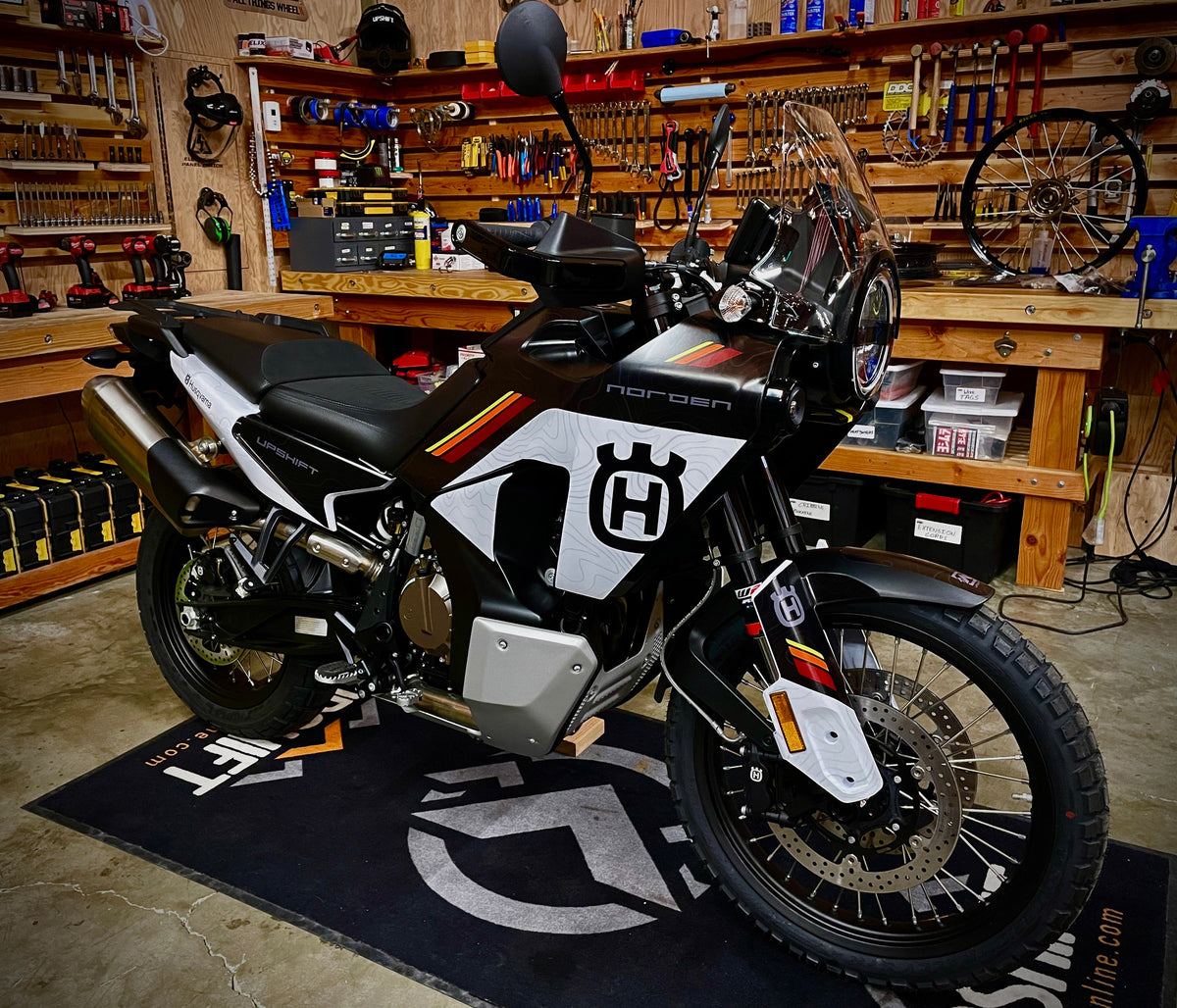 Shop photo of a Husqvarna Norden 901 adventure motorcycle with the Black Split Topo Graphics kit. This design features a topo pattern and some short stripes in red, orange and yellow.  Shown on the standard Norden 901